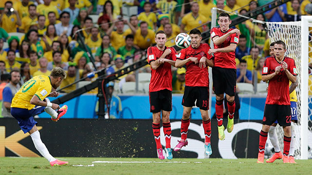 Brazil's Neymar, left, takes a free kick against Mexico's defensive wall during the group A World Cup soccer match between Brazil and Mexico.